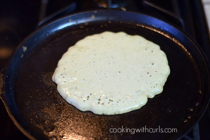 Pancake batter on a cast iron skillet.