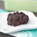 paleo sweet potato brownie on a square white plate with a green baking dish in the background