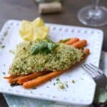 Rosemary and Panko Crusted Salmon on a bed of carrots and asparagus with a carved lemon half in the corner of a square white plate.
