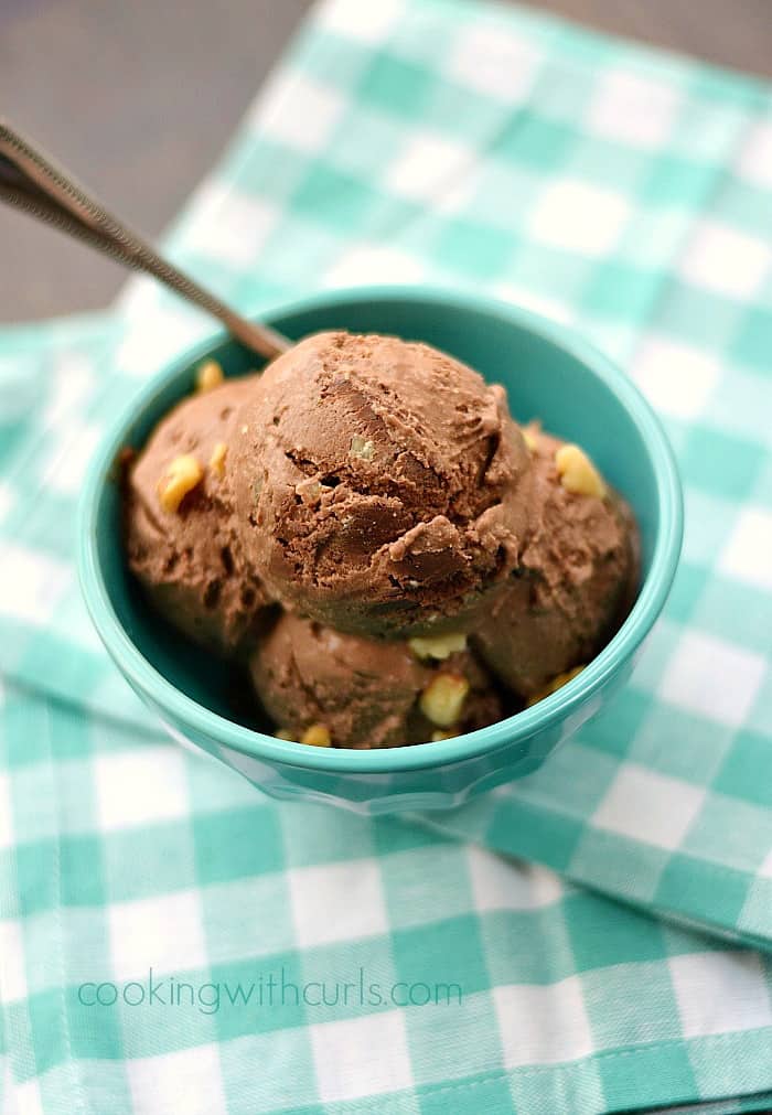 chocolate walnut ice cream in a turquoise bowl sitting on a turquoise and white checkered napkin.