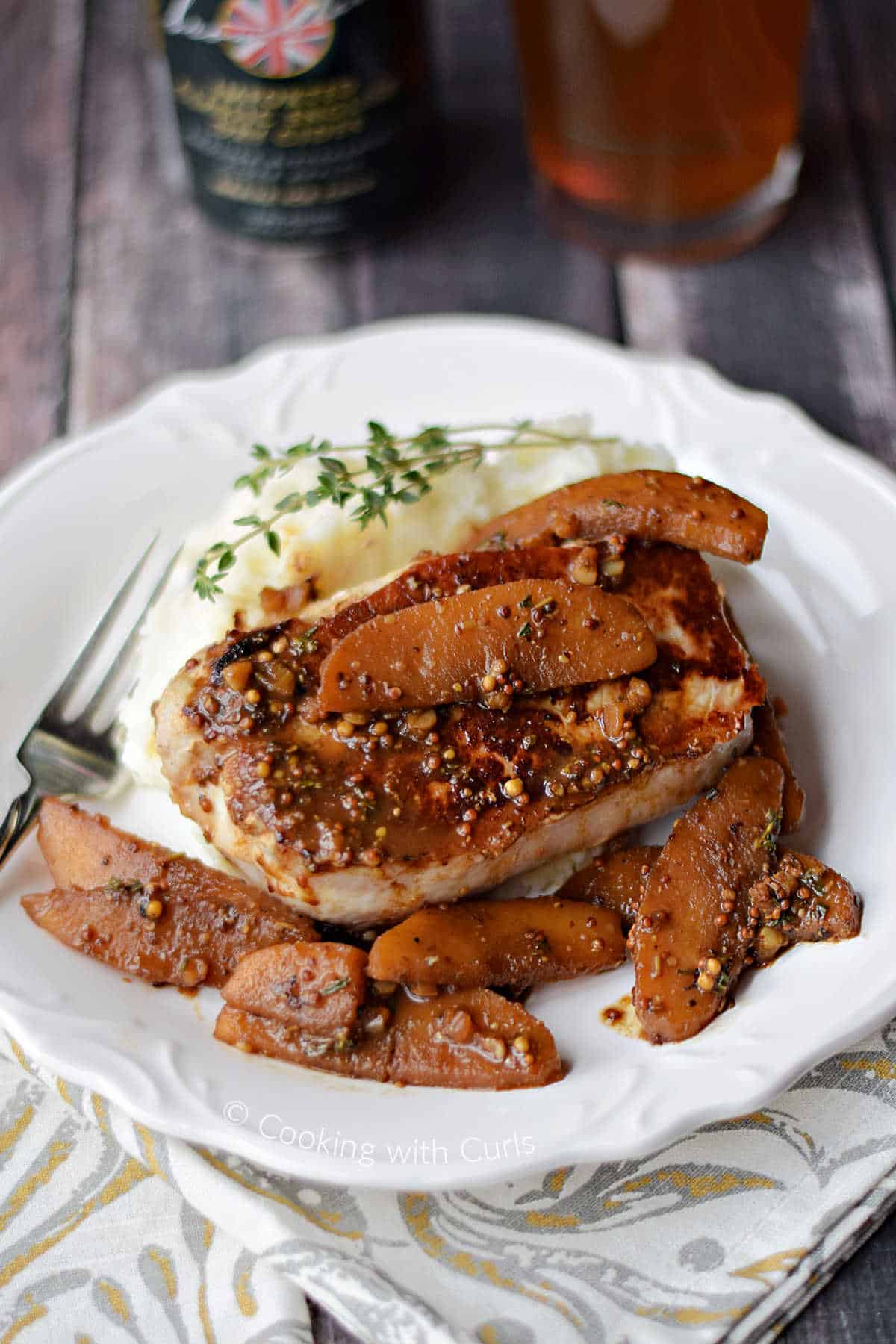 Boneless pork chop topped with apples in cider sauce over mashed potatoes.