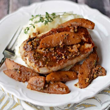 Boneless pork chop topped with apples in cider sauce over mashed potatoes.