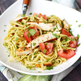 Guacamole Linguine with Chicken in a square white bowl with a wood handled fork in the upper left corner.