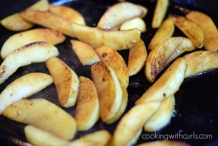 Cooked apple wedges in a cast iron skillet.