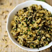 A serving bowl filled with savory wild and brown rice pilaf with fresh chopped parsley on top