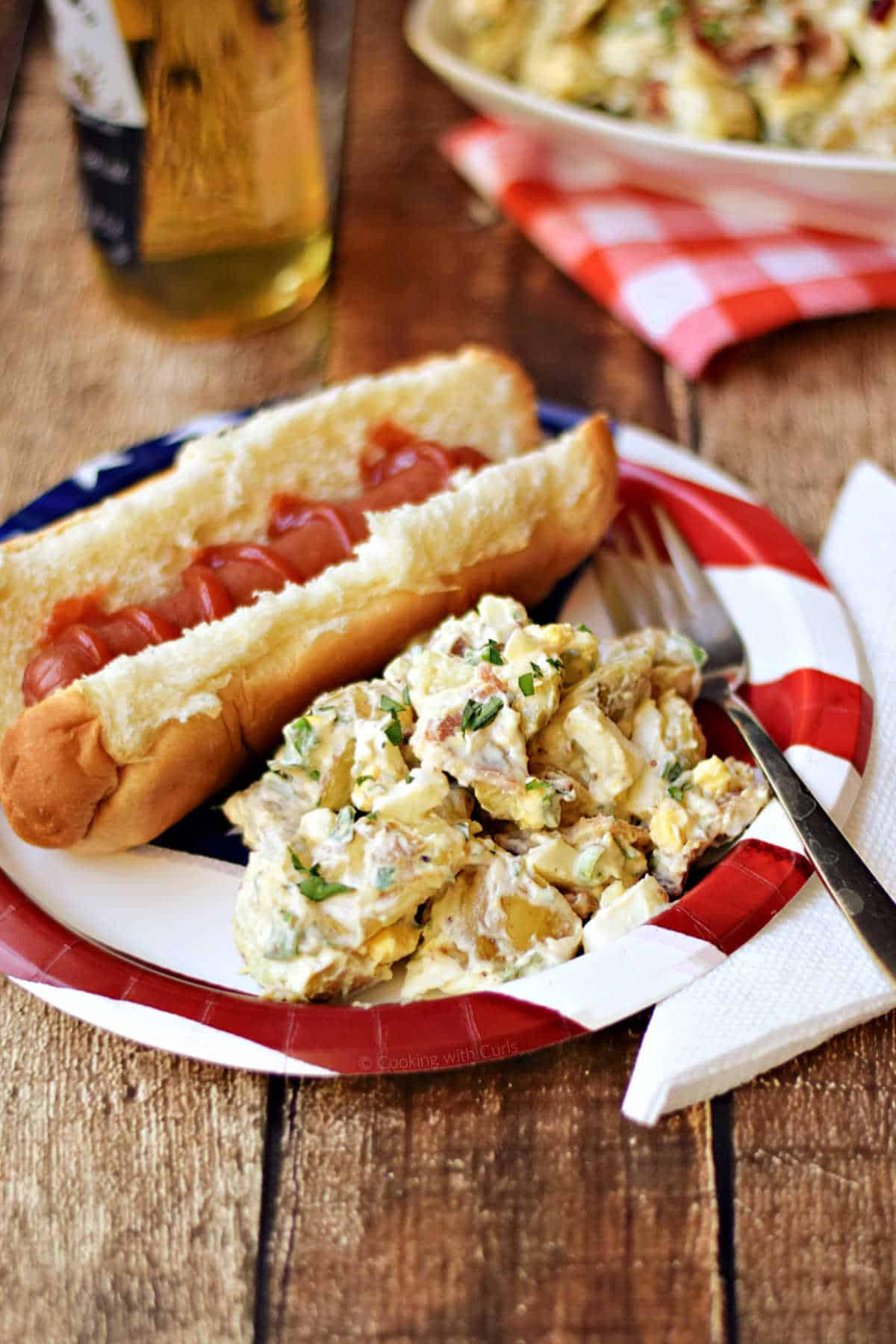 Bacon potato salad and hot dog on a patriotic plate.