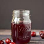 Cherry Simple Syrup in a glass mason jar surrounded by fresh cherries.