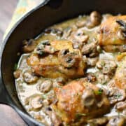 Chicken thighs covered in a mushroom sauce in a cast iron skillet.