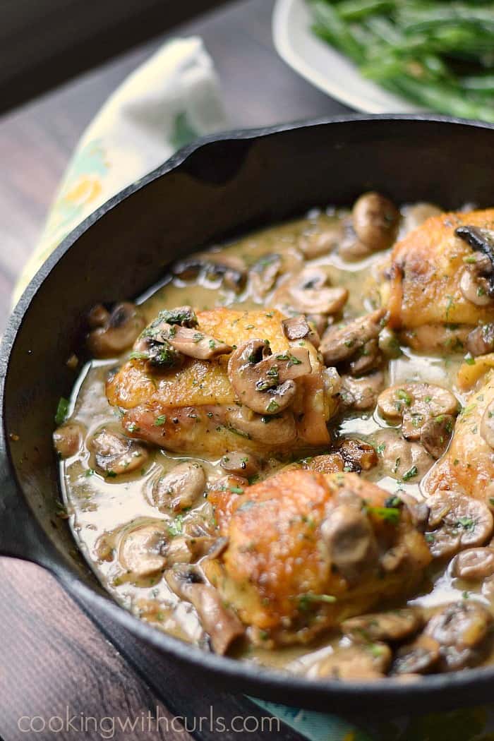 Chicken thighs covered in a mushroom sauce in a cast iron skillet.