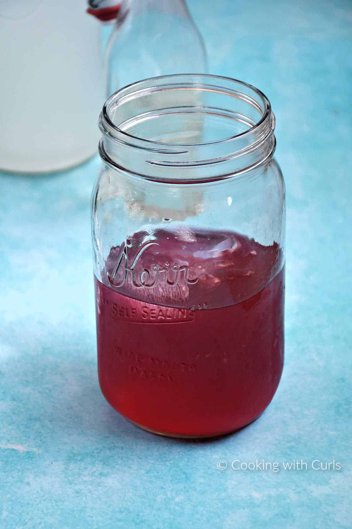 Passion tea and lemonade mixed in a mason jar with ice cubes.