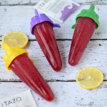 Three Passion Tea Lemonade Popsicles laying on a white, weathered board.