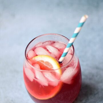 Passion Tea Lemonade in a small glass with a blue and white striped paper straw