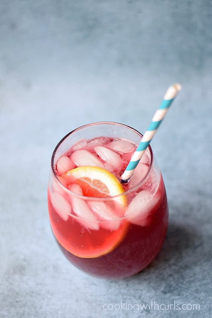 Passion Tea Lemonade in a small glass with a blue and white striped paper straw