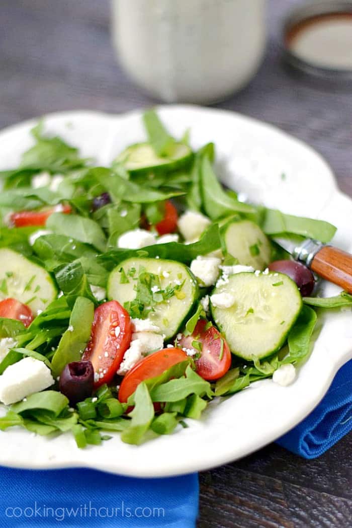 A fresh Greek Salad on a white plate sitting on a bright blue napkin.