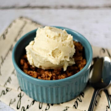 A small ramekin filled with rhubarb crisp and topped with a scoop of vanilla ice cream.