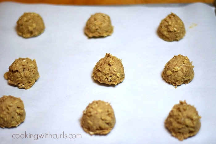 Nine oatmeal cookies on a parchment paper lined baking sheet.