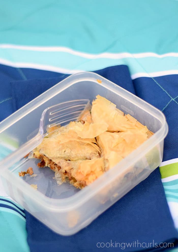 Five sections of filo meat pie in a plastic picnic container.