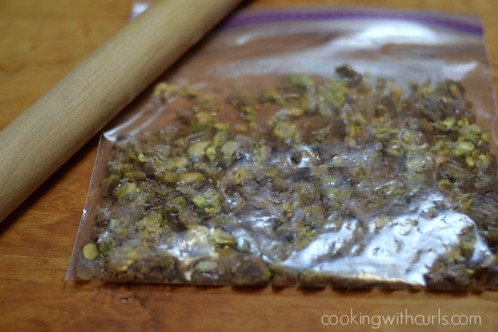 Hardened pistachio praline in a zipper top bag with a rolling pin on the side.