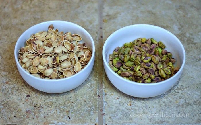 One small bowl of pistachio shells and one small bowl of shelled pistachios on the counter.