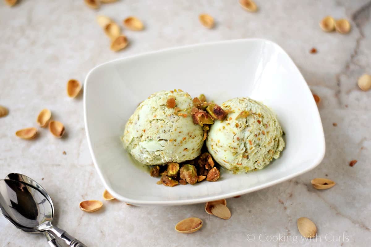 Two scoops of Pistachio Ice Cream with pistachio praline in a white bowl.