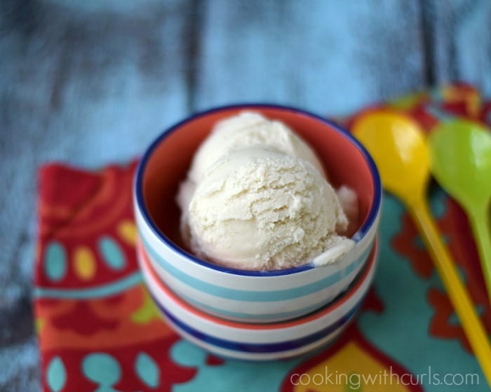 Two scoops of vanilla ice cream in a striped bowl.