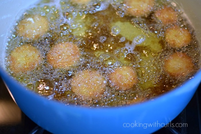 Ten golden Fried Zucchini in a pot of hot oil.