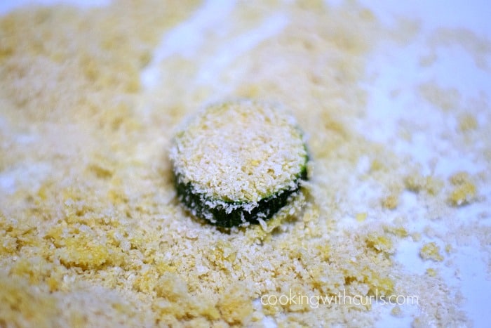 Egg dipped zucchini slice on a plate of panko breadcrumbs.
