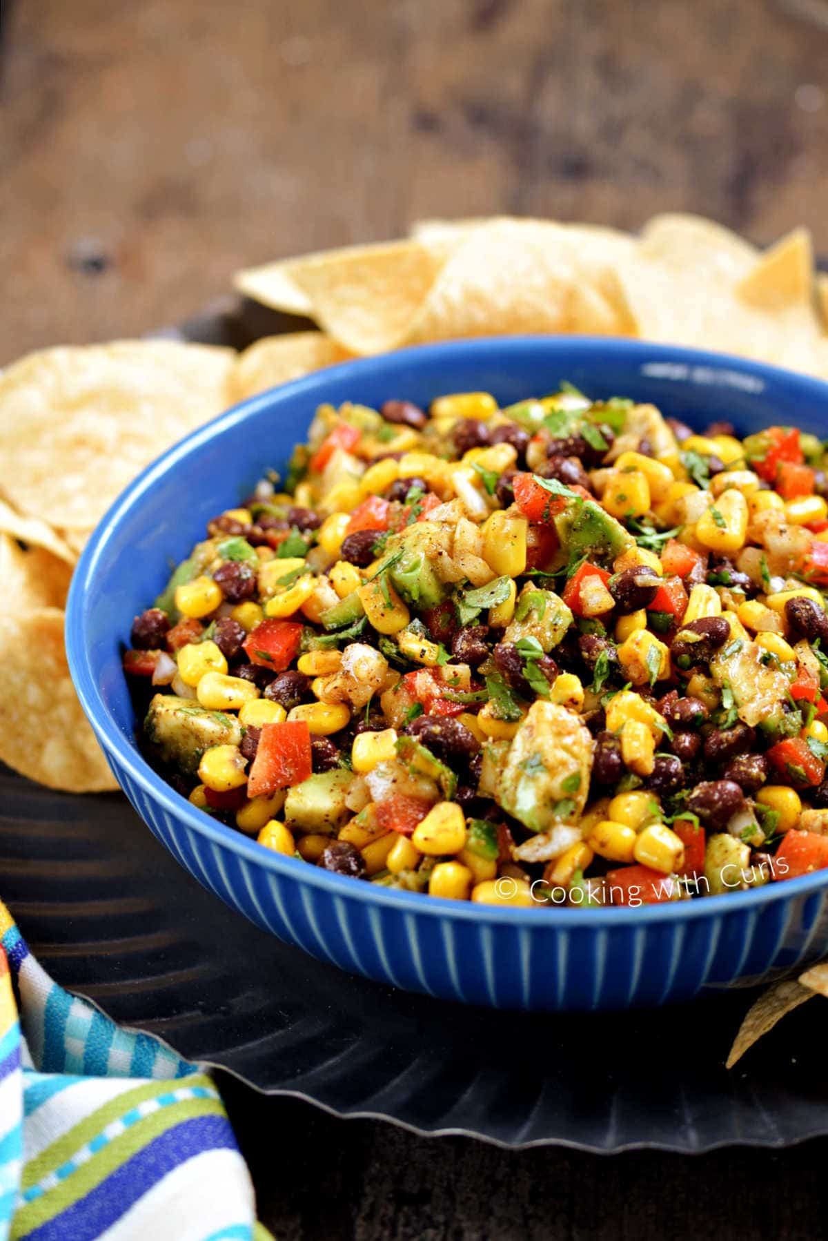 Black bean and corn salsa in a serving bowl surrounded by tortilla chips.