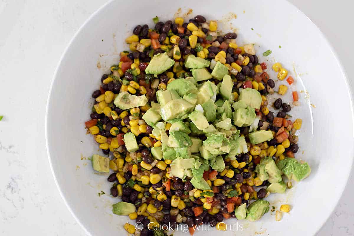 Chunks of avocado on top of the black beans, corn, peppers, and dressing.