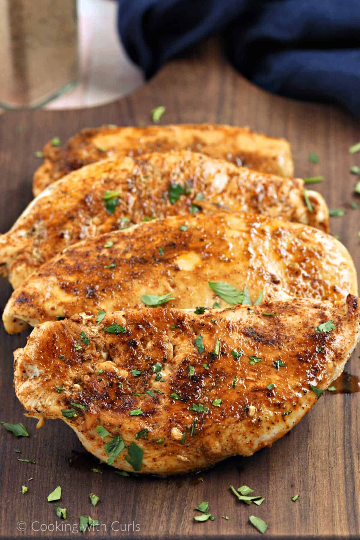 Four chicken breasts cooked with southwest seasoning stacked on a board.