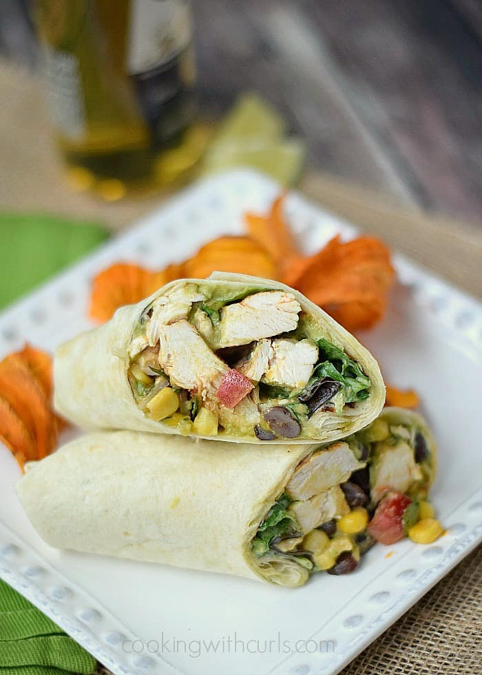 Southwest Chicken Salad Wrap cut in half sitting on a square white plate with sweet potato chips in the corner