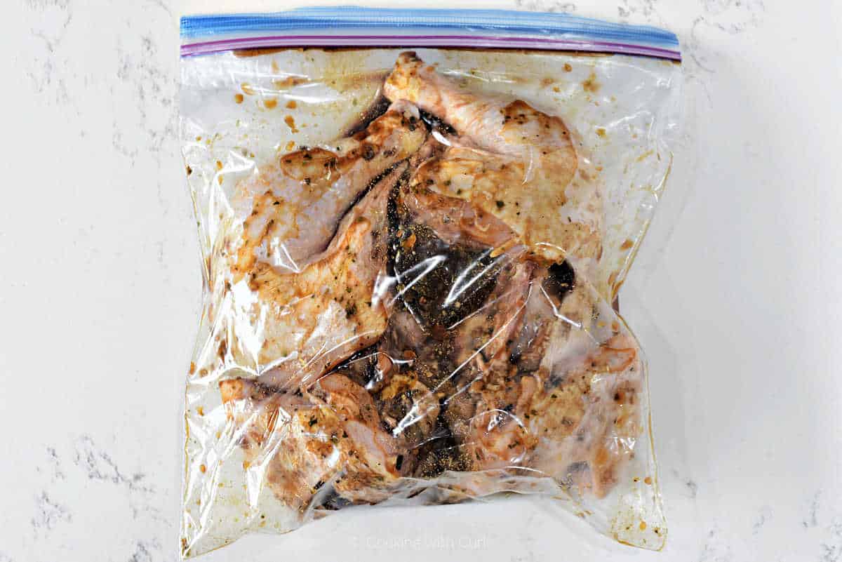 Whole spatchcocked chicken with marinade in a zipper top bag.