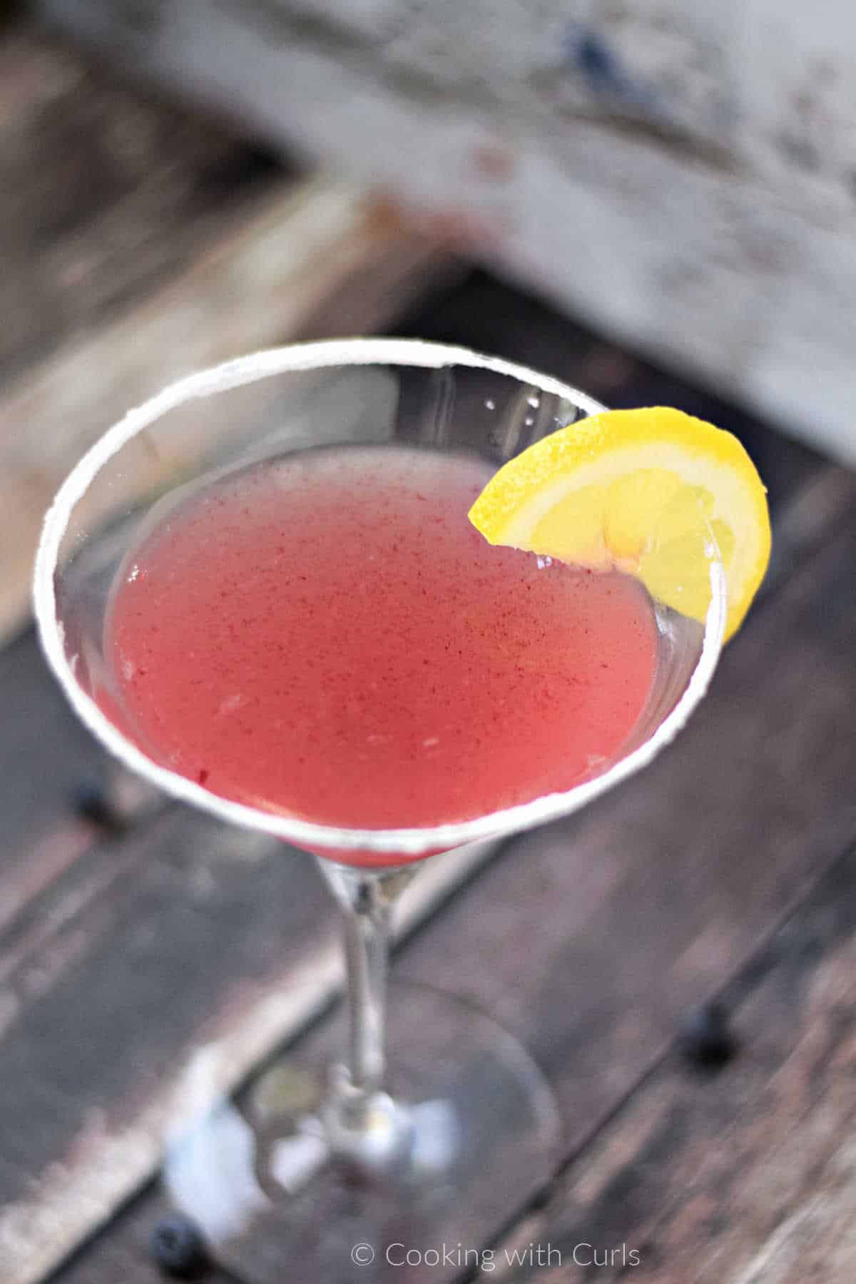 huckleberry lemon drop marini in a sugar rimmed martini glass garnished with a lemon slice.