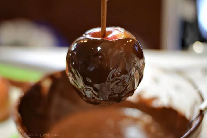 A caramel apple dipped into melted chocolate.