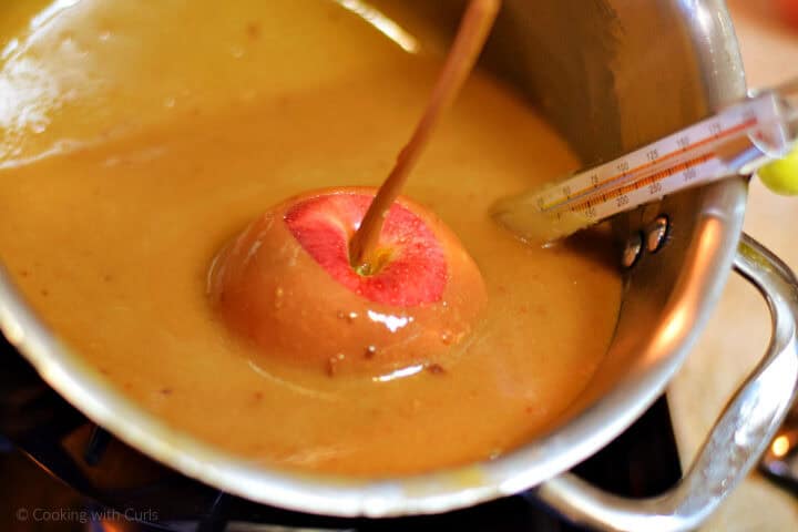 Apple with stick dipped into hot caramel.