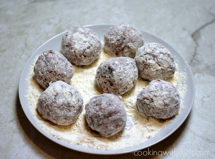 Meatballs dredged in flour on a plate.