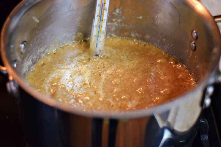 Bubbling caramel in a large pot with candy thermometer.