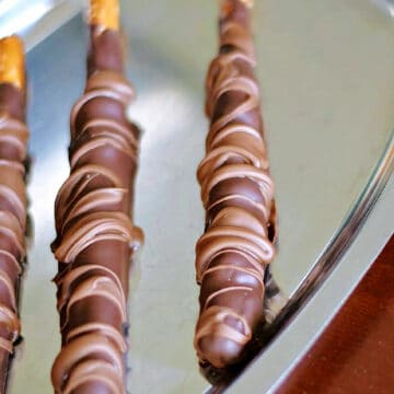 Three Chocolate Caramel Pretzel Rods on a silver tray.