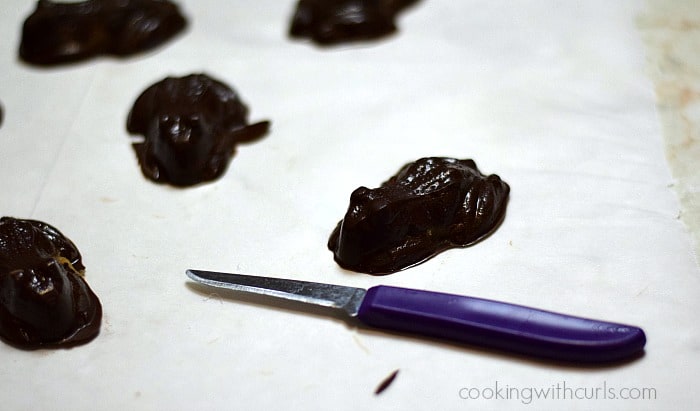 A small knife laying on parchment paper next to chocolate frogs.