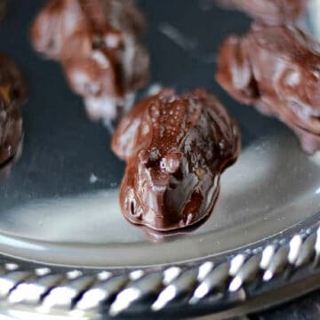 Five frog shaped chocolate candies on a silver tray.