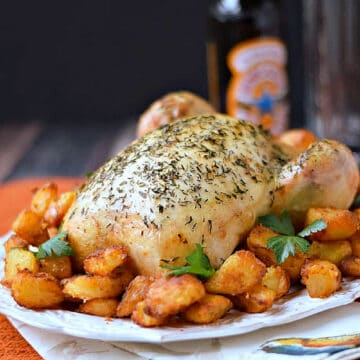 Classic Roast Chicken with roast potatoes on an oval serving platter. 