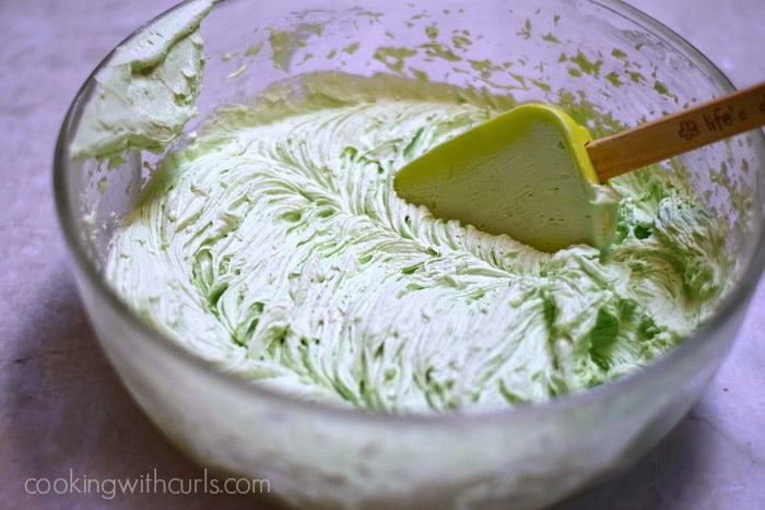 Frosting mixed with green food coloring in a large bowl.