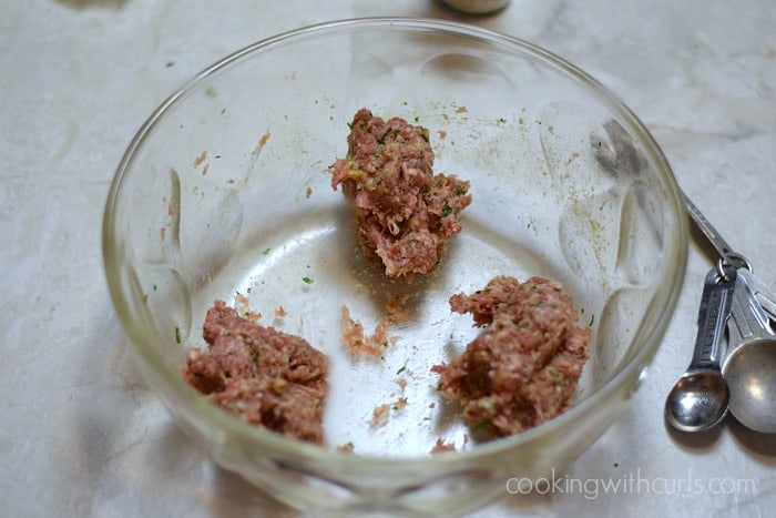 Sausage filling divided into three balls in a large glass bowl.