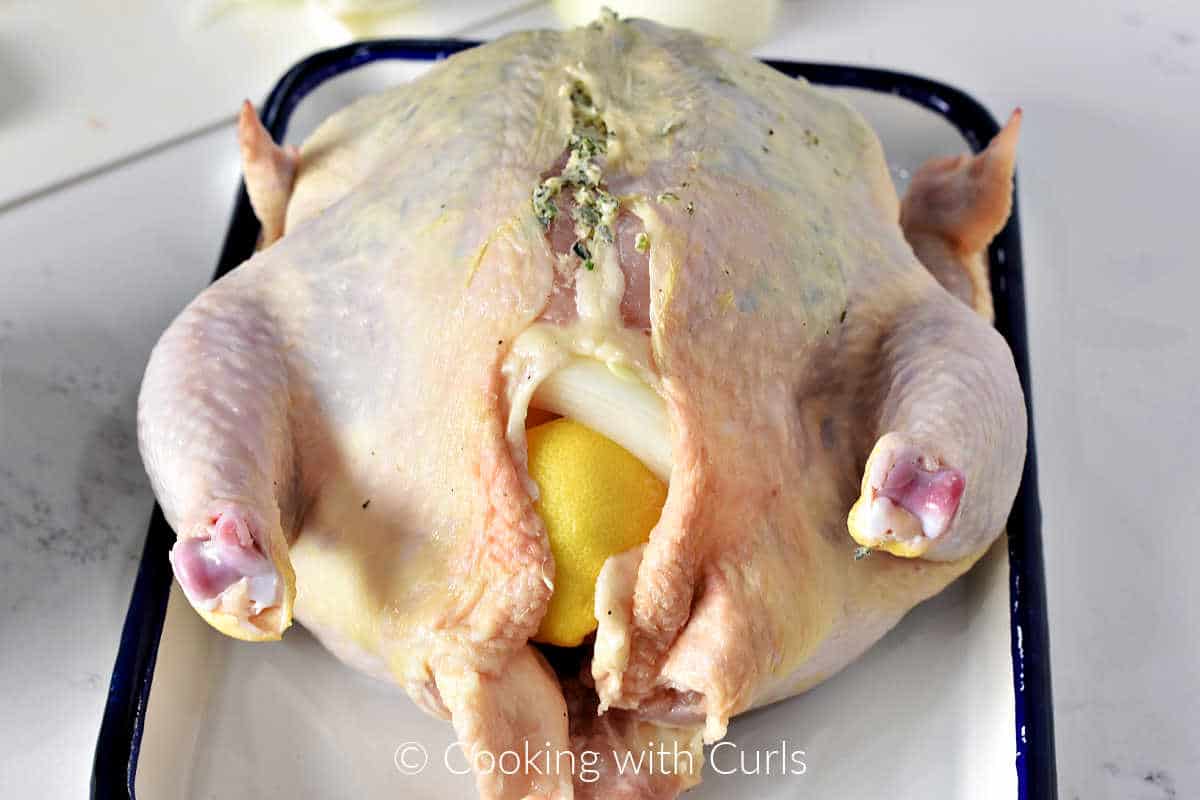 chicken-stuffed-with-lemon-and-onion-with-herb-butter-under-the-skin-sitting-on-a-tray.