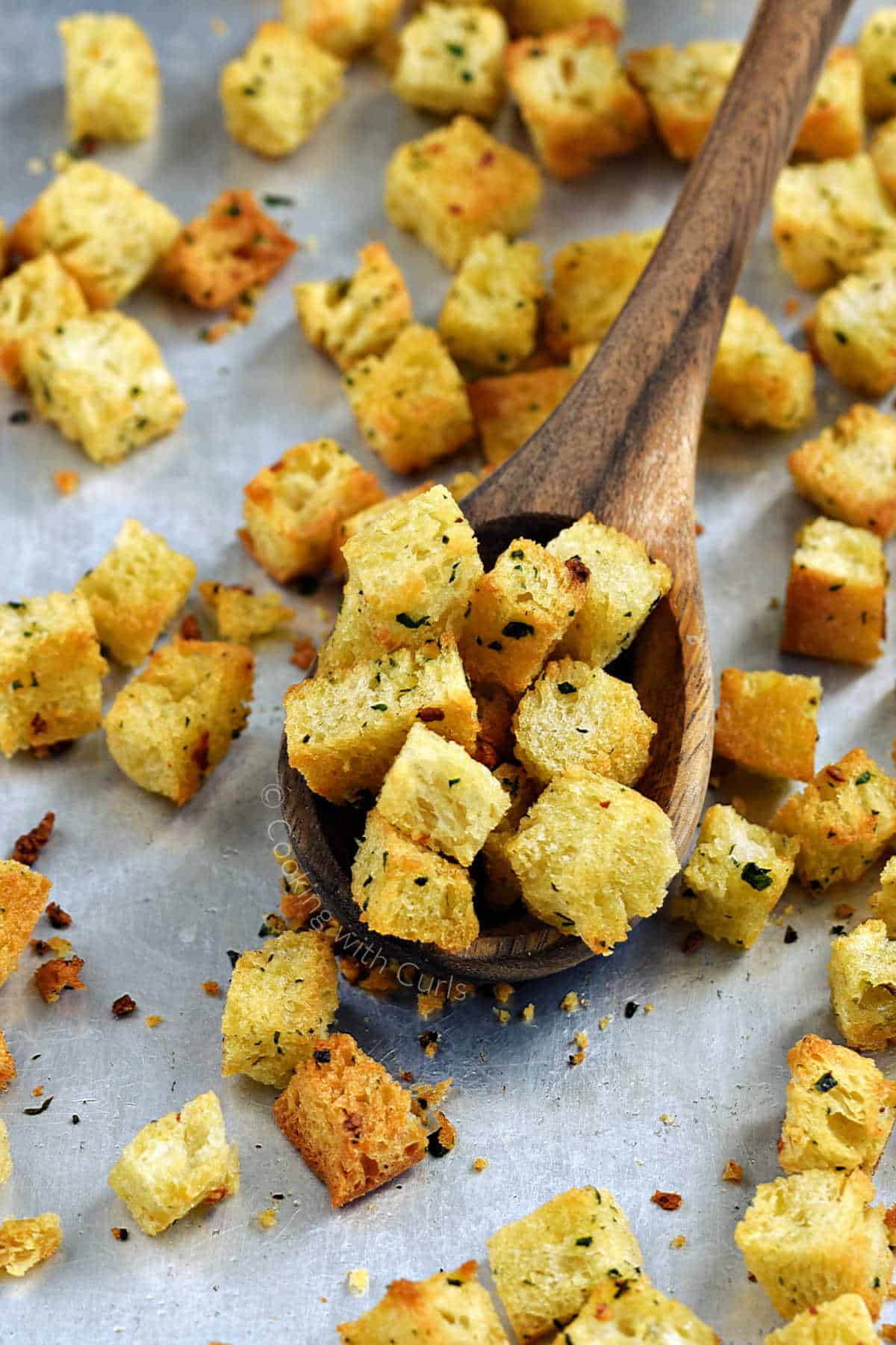 Homemade-crunchy-garlic-croutons-in-a-wood-spoon-on-a-baking-sheet.