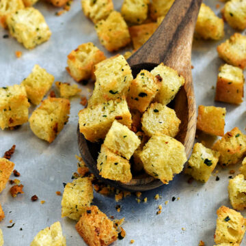 Homemade-crunchy-garlic-croutons-recipe-in-a-wood-spoon-on-a-baking-sheet.