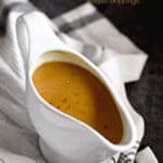 Rich, brown turkey gravy in a white gravy boat sitting on a black and white napkin with a title graphic across the top.