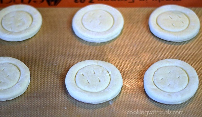 Six puff pastry circles on a silicone lined baking pan.