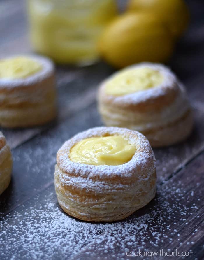 Four puff pastry tart shells filled with lemon curd.