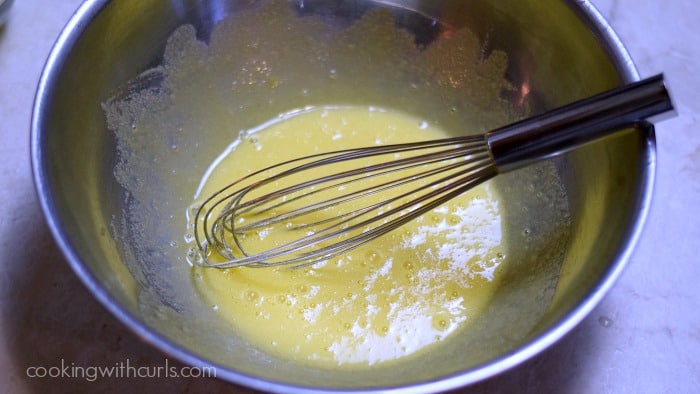 Eggs, lemon juice, salt, and sugar whisked together in a large stainless steel bowl.